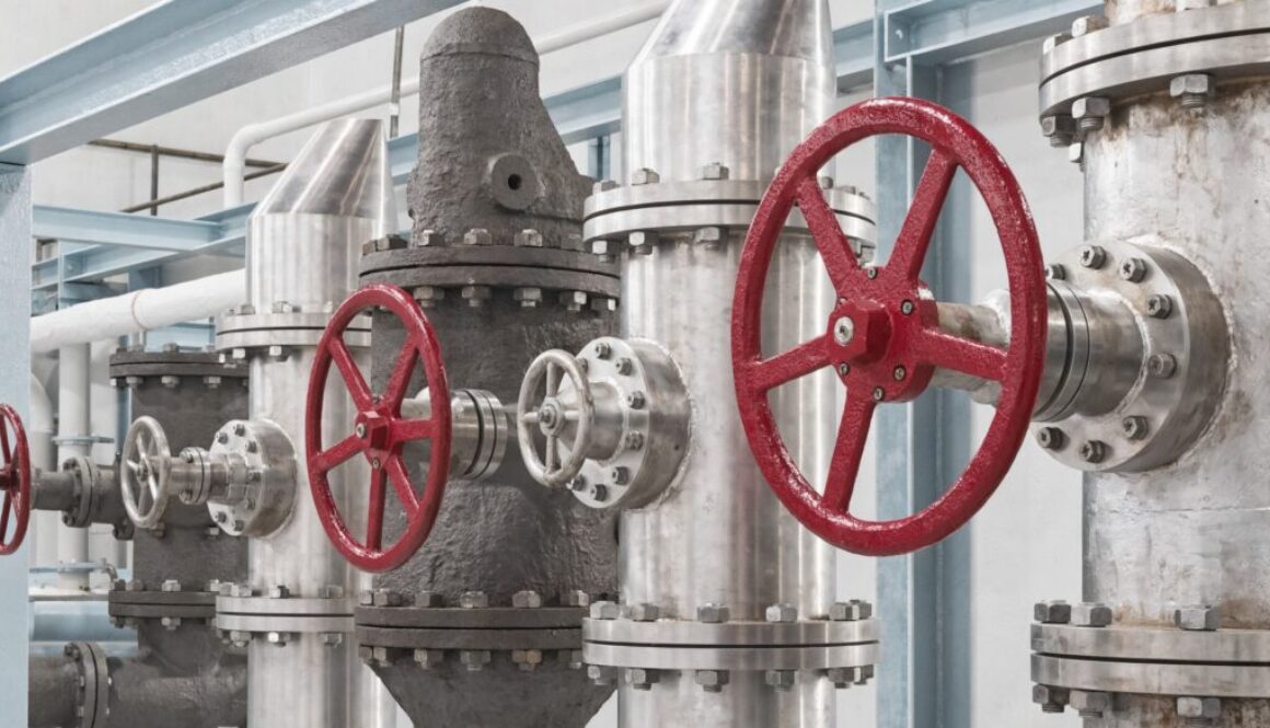 Industrielle Absperrschieber verschiedener Bauform am Rohrleitungsstrang mit roten Handrädern und Flanschverbindungen